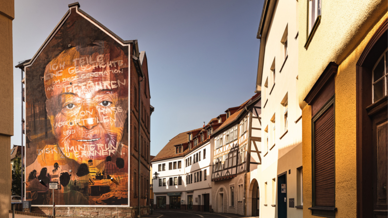 Viele Gebäude zieren Graffitis namhafter Künstler, wie das Porträt der Holocaust-Überlebenden Magda Brown von AKUT (Falk Lehmann). © djd/Schmalkalden/Axel Bauer