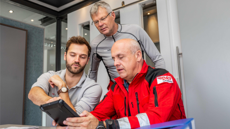 Mitarbeiter der DRF Luftrettung arbeiten zusammen an einem Tablet. ©DRF Luftrettung 