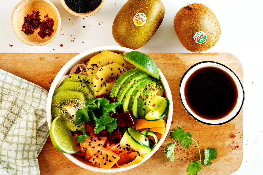 In der Poke Bowl mit Kiwis, Nudeln, Lachs und Ponzu-Sauce sind sowohl die traditionellen grünen Früchte als auch ihre Schwestern mit dem leuchtend-gelben Fruchtfleisch enthalten. Foto: DJD/Zespri