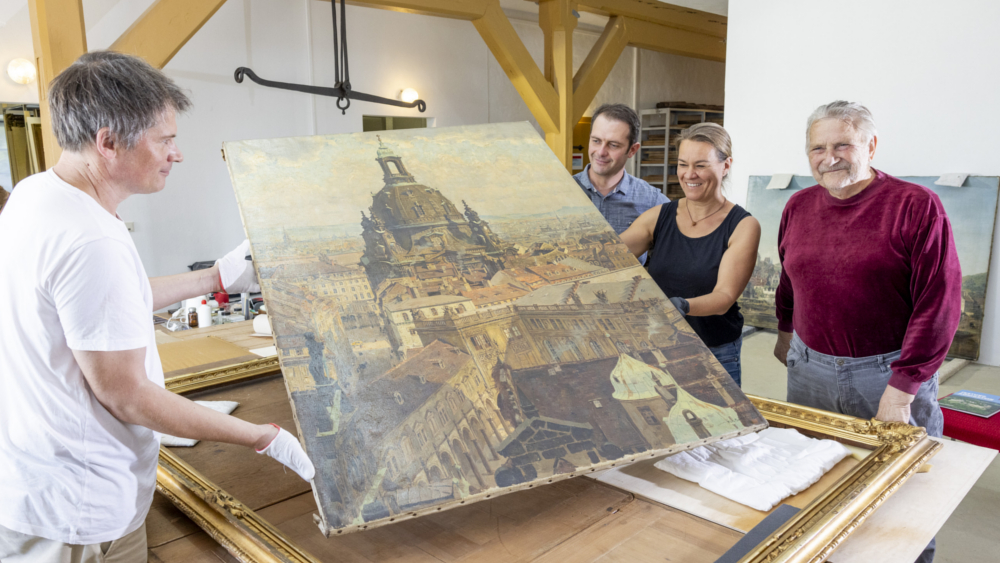 Restauratoren Tobias Lange und Evelyn Adler (halten das Bild), 3.v.r. Markus Bitterlich und Dresdner Kunstsammler Wolfgang Donath (rechts), Bild „Die Frauenkirche“ von Fritz Beckert, 1944, Öl auf Leinwand, ca. 1,60 mal 1,20 Meter ©Marko Förster/ Festung Königstein gGmbH