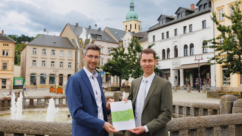 Der Präsident der Landesdirektion Sachsen, Béla Bélafi (rechts im Bild), übergibt dem Oberbürgermeister der Großen Kreisstadt Sebnitz, Ronald Kretzschmar, eine Bedarfszuweisung in Höhe von 1,4 Millionen Euro für die Ausrichtung des Tag der Sachsen 2025. Foto:  Luisa Aehlig