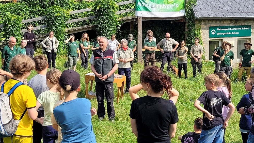 2Uwe Borrmeister (m. l.), Leiter der Nationalpark- und Forstverwaltung von Sachsenforst, und Margitta Jendrzejewski (m. r.), Leiterin der Naturbildungsstätte Sellnitz, begrüßten die Schülerinnen und Schüler, Lehrkräfte sowie Mitarbeitende und Freiwillige der Nationalpark- und Forstverwaltung zu den diesjährigen Waldjugendspielen in der Nationalparkregion Sächsische Schweiz. Foto:ĦP Mayr