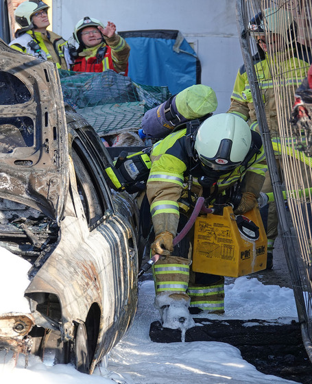 Feuerwehrleute führen Restablöschungen an einem PKW durch, Führungskräfte besprechen sich im Hintergrund. © Roland Halkasch